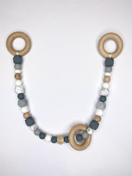 Grey, white and marble beads on long string wth wooden rings at each end annd a wooden ring hanging freely over beads