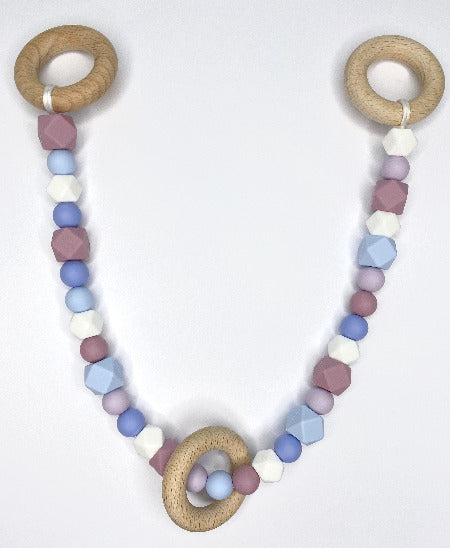 Various shades of purple beads, plus white beads attached to long string with wooden rings at each end and another wooden ring hanging freely over beads.
